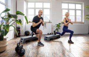 Mann und Frau machen gemeinsam in einem Wohnzimmer Functional Übungen. Sie nutzen jeweils ein Step-Board der Marke Taurus.